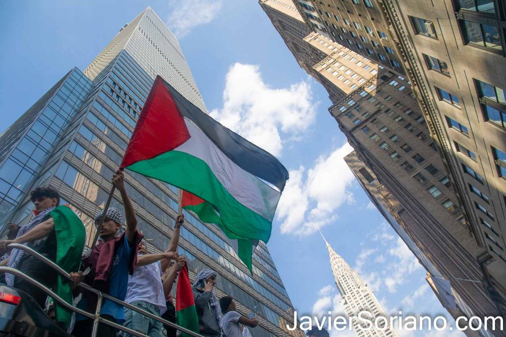 Tuesday, May 18, 2021. New York City - Thousands of Palestinians, Jews, Latinas, Latinos, Asians, Blacks, Whites, and others shut down different streets in New York City to support the Palestine Strike. BDS said, “Palestinians in Jerusalem and across Historic Palestine are observing General Strike (on Tuesday, May 18, 2021) to protest Israel’s massacres in Gaza and settler-colonial and apartheid repression and ethnic cleansing against Palestinian communities everywhere.” People gathered in front of the zionist (Israel) mission to the United Nations. After the rally, demonstrators marched through different streets in Manhattan. Organizers called the demonstration: “Shut down Zionism to support the #PalestineStrike.” The demonstration was organized by NY4Palestine, Al-Awda NY: The Palestine Right to Return Coalition, Samidoun Palestinian Prisoner Solidarity Network, Within our Lifetime • United for Palestine, Jews for Palestinian Right of Return and Labor for Palestine. THIS PHOTO: Protesters waving flags of Palestine. In the background, the Chrysler Building and other skyscrapers in Manhattan. Photo by Javier Soriano/www.JavierSoriano.com
