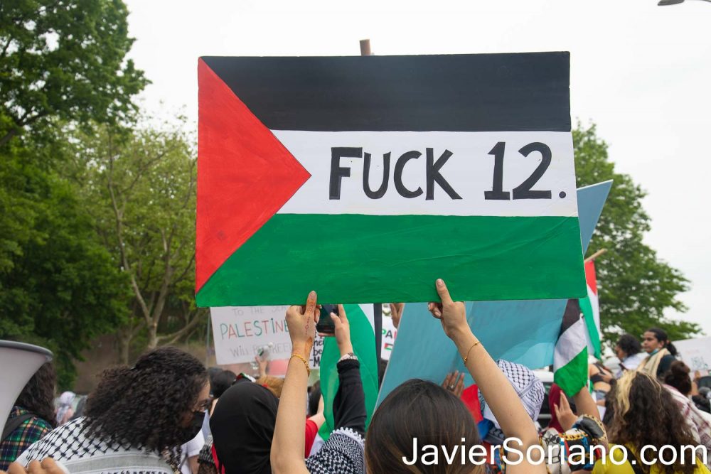 Saturday, May 22, 2021. New York City - Thousands of anti-zionist Palestinians, Jews, Native Americans, Latinas, Latinos, Blacks, Asians, and others rallied and marched to DEFEND PALESTINE. Demonstrators gathered at Queens BLVD and 45 Street in the borough of Queens. After the rally, they marched to Astoria, Jackson Heights, etc. in the same borough of Queens. THIS PHOTO: A female protester with a sign that reads: "FUCK 12" (the phrase and slang “Fuck 12” or “Fuck Twelve” basically means fuck the police, but more specifically it's means fuck the police drug unit). Photo by Javier Soriano/www.JavierSoriano.com
