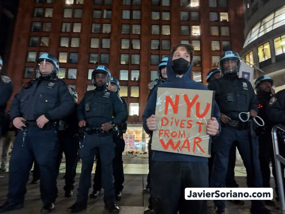 Monday, April 22, 2024. Manhattan, New York City - On April 22, 2024, students and faculty began the first “Gaza Solidarity Encampment” at New York University (NYU), demanding NYU to divest from companies with ties to the zionist, apartheid, terrorist entity. There were hundreds of peaceful protesters inside and outside the encampment. THIS PHOTO: On the same day, after NYPD officers arrested at least 130 peaceful New Yorkers, a protester with the sign, “NYU divest from war.” Behind the protester there is an army of NYPD cops. Photo by Javier Soriano/www.JavierSoriano.com.